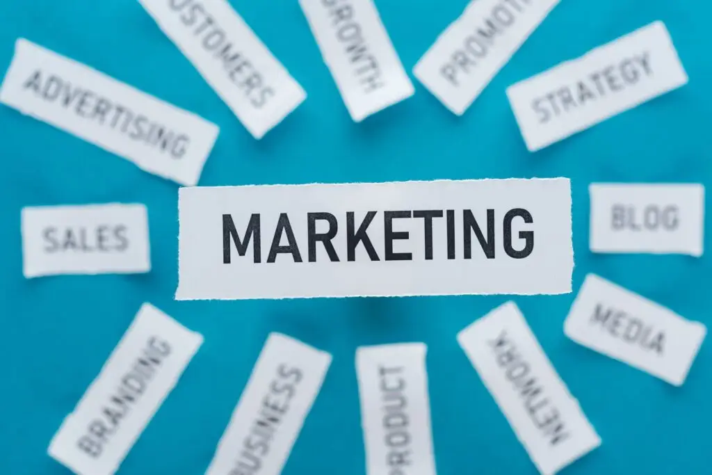 Digital Marketing Training - Selective focus of word marketing and components related to marketing on pieces of paper on blue