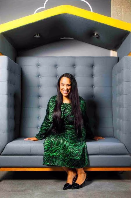 Managing Director of apprenticeship provider, sat in a large grey and yellow chair. Head down and smiling